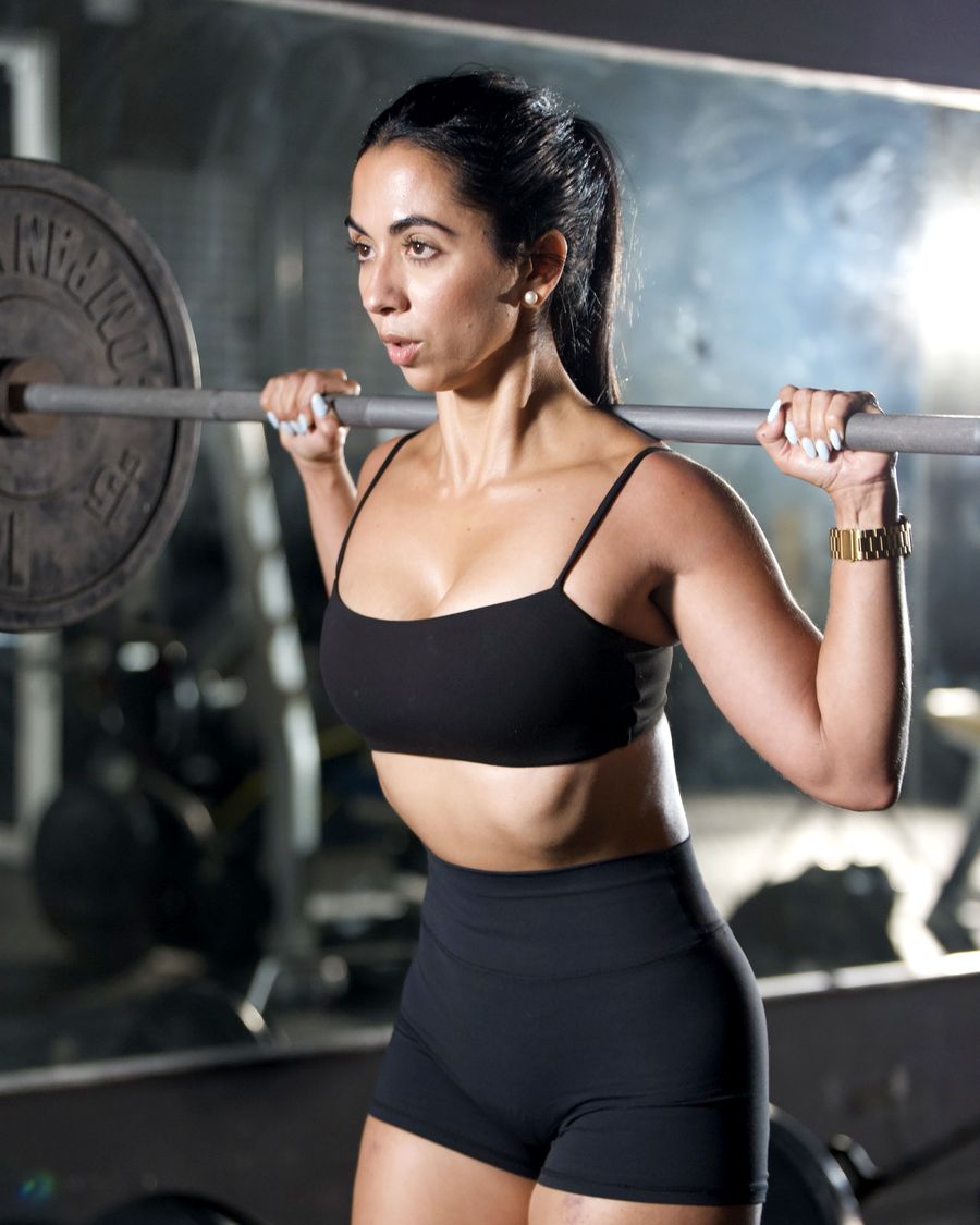 Trainer with a loaded barbell across her shoulders