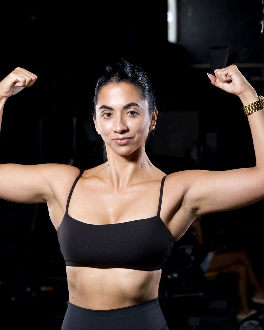 Trainer flexing both arms in the gym