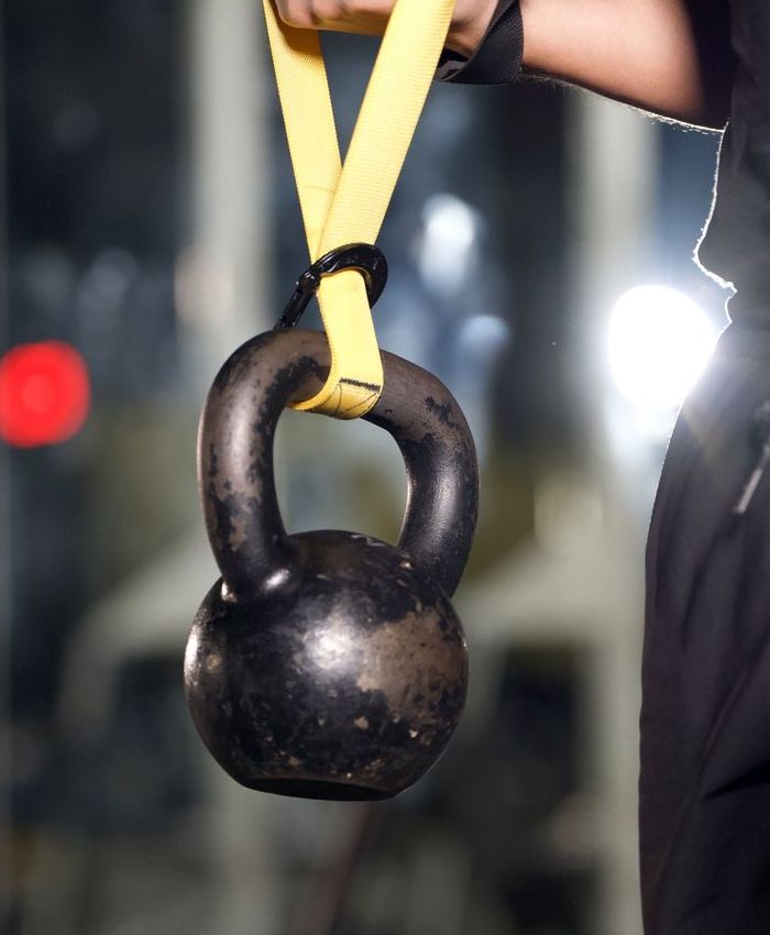 Black kettlebell hanging from a yellow strap