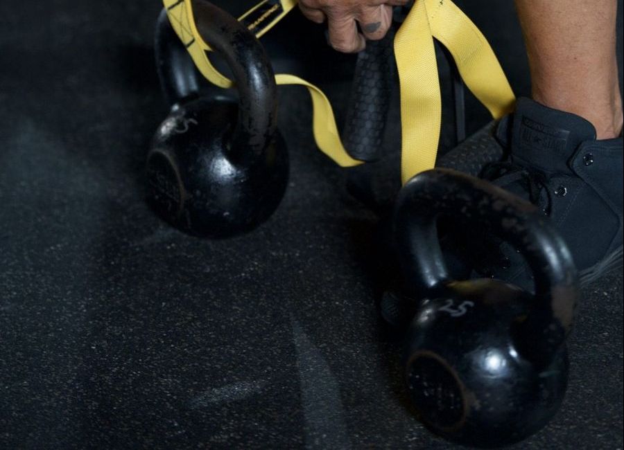 Two kettlebells with yellow straps on the gym floor
